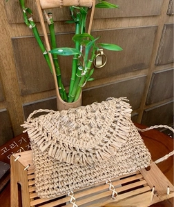 Close-up of bohemian beige paper rope woven shoulder bag featuring thick fringe trim