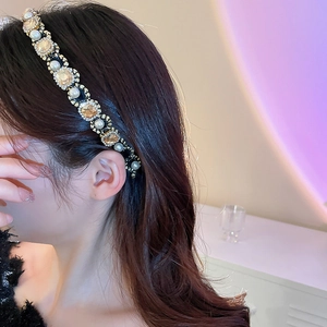 Detail of vintage headband with champagne gems and white pearls worn by a model