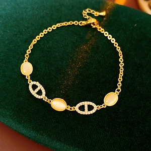 Détail macro du bracelet doré avec pierre œil de chat et maillons sertis de zircons