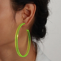 Close-up of translucent neon green acrylic hoop earring worn by a model