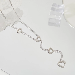 Detailed view of silver heart-shaped pendants reflected on a clear mirror surface