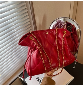 Macro detail of red quilted chain bag with gold hardware and drawstring closure