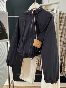 Detail view of black lightweight windbreaker featuring adjustable drawstring and elastic cuffs