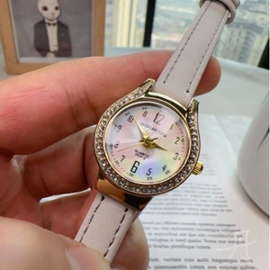 Elegant ladies quartz watch with gold diamond bezel and white leather strap on wrist