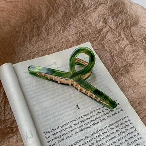 Detail of green marble acetate hair claw clip with gold metal teeth on vintage book