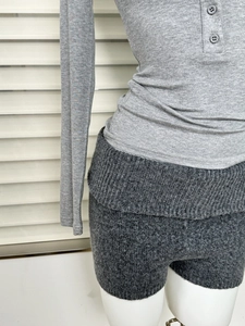 Détail d'un haut Henley en tricot gris et d'un short taille haute au tissu texturé