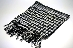 Detailed close-up of houndstooth desert scarf with decorative fringe on a white background