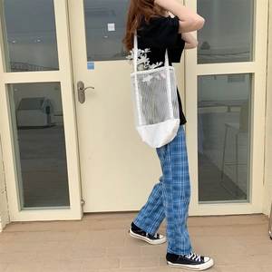 Close-up of blue and white plaid wide-leg pants paired with a white mesh tote bag