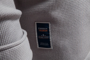 Close-up of light gray waffle knit fabric texture and dark blue fashion design patch