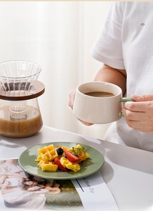 Detailansicht einer nordischen Kaffeetasse aus Keramik mit grünem Griff im Lifestyle