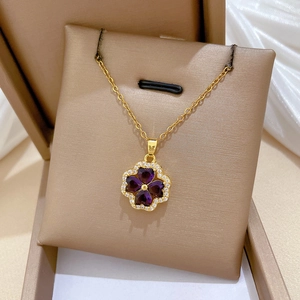 Detail of clover pendant with purple heart gemstones and tiny crystals in a jewelry box