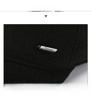 Detail of a black baseball cap featuring a silver metal plate with fashion engraving