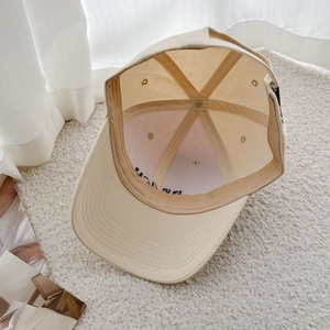 Internal detail of beige cotton baseball cap showing sweatband and adjustable buckle