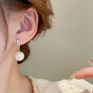 Elegant pearl drop earrings with rectangular zircon stone shown on model's ear