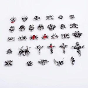 Macro shot of silver gothic nail charms including skulls, crosses and spiders with rhinestones
