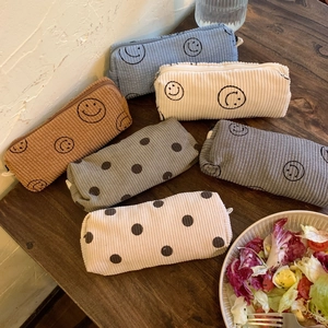Detailed view of assorted corduroy cosmetic bags with smiley face and polka dot patterns