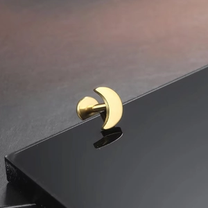 Macro shot of gold moon-shaped titanium flat back stud earring with reflective surface