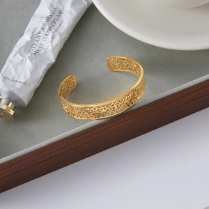 Detail shot of a golden hollowed-out vintage cuff bracelet on a velvet display tray