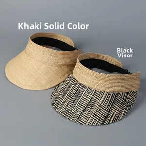 Detail of raffia sun visors featuring khaki weave and black striped brim with adjustable strap