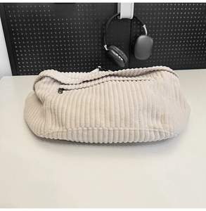 Detail of beige corduroy cloud bag showing soft ribbed texture and zipper closure