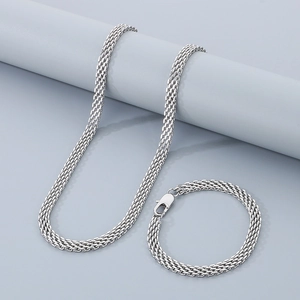 Détails d'un ensemble collier et bracelet en maille argentée sur un présentoir gris