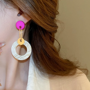 Macro shot of geometric acrylic earrings with fuchsia and marble pattern on a model