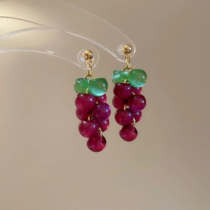 Detail view of purple resin grape tassel earrings with green leaf beads and gold accents