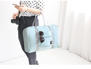 Close-up of light blue foldable travel bag featuring a front pocket and durable nylon texture