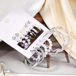 9-piece butterfly and pearl earring set with silver hoops and studs on elegant beige silk