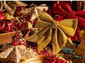 Detail of red and gold Christmas bows with glitter star beads and festive ornaments