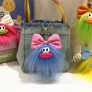 Portachiavi mostro di peluche blu con fiocco rosa appeso a una borsa di jeans
