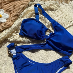 Detail view of navy blue bikini set with gold rings on a crochet beach cover-up