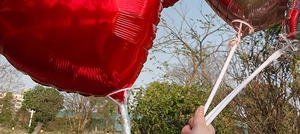 Outdoor shot of an 18-inch red heart foil balloon held against a bright blue sky
