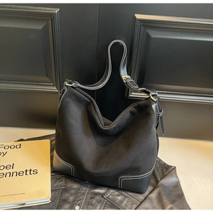Close-up of black suede tote bag showing contrast white stitching and premium texture