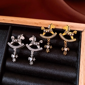 Detailed close-up of vintage horse stud earrings with zircon and cross pendants