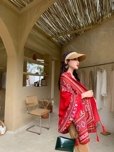 Detail of red ethnic print shawl with tassels and vintage boho patterns for beach travel