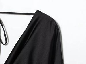 Détail des fines bretelles et du drapé en satin sur cette robe de soirée noire