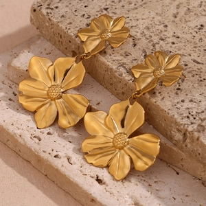 Detail of 18K gold-plated double floral drop earrings on a beige stone background