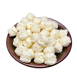 Ivory nut lion head carved beads for jewelry making in a dark ceramic bowl