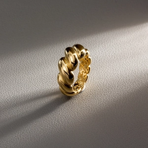 Detailed macro view of gold-plated twisted ring with hollow H letter pattern design