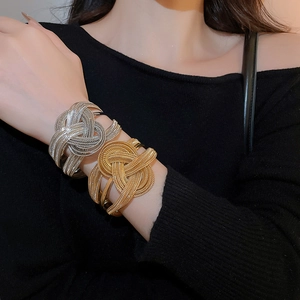 Detail view of gold and silver multi-layer braided chain open cuff bracelets on model