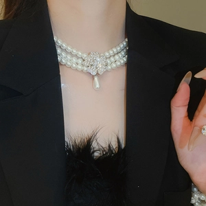 Detail of necklace with white pearls, diamond flower pendant and drop pearl tassel charm