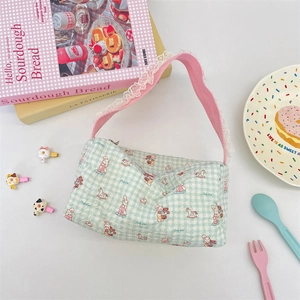 Close-up of green checkered canvas handbag with cute cartoon motifs and white lace trim