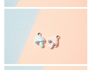Close-up of mint green and light pink mushroom charms with enamel finish and metal loops