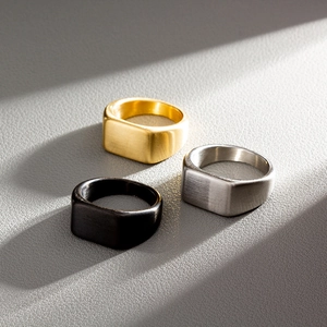 Macro detail of brushed stainless steel signet rings in gold, silver, and black finishes
