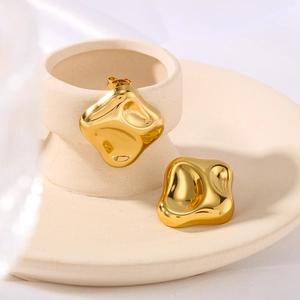 Irregular square gold-plated stainless steel stud earrings on a beige ceramic tray