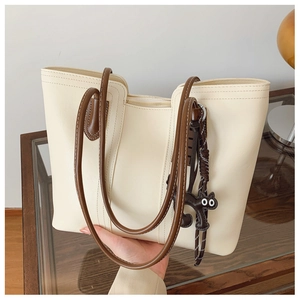Detail of off-white tote bag with brown straps and a cute black cat charm accessory