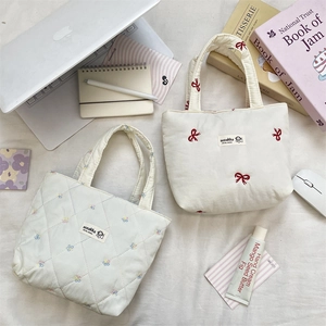 Detail view of Korean style quilted tote bags with elegant bow and floral embroidery.