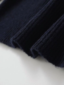 Dettaglio macro della maglia a coste blu scuro che mostra la morbida lana di alpaca