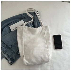Close-up of cream canvas tote bag showing herringbone texture and spacious interior